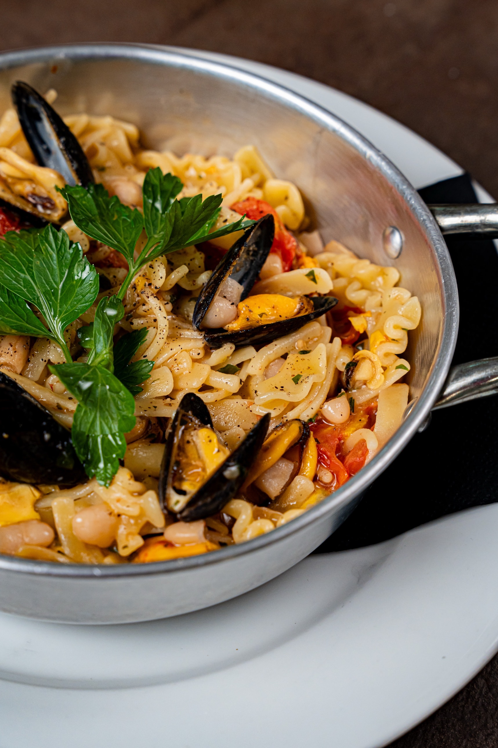 Dettaglio del padellino con cozze, fagioli e prezzemolo